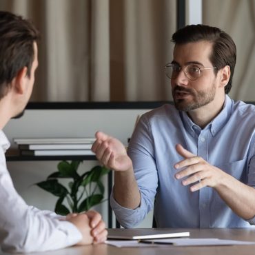 Confident manager in glasses consulting client at meeting in office