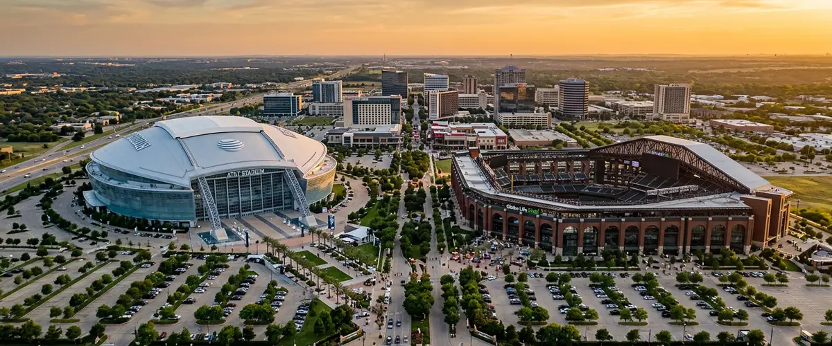 Arlington Texas Entertainment District at golden hour with Globe Life Field, AT&T Stadium, and the downtown skyline visible against a warm Texas sky