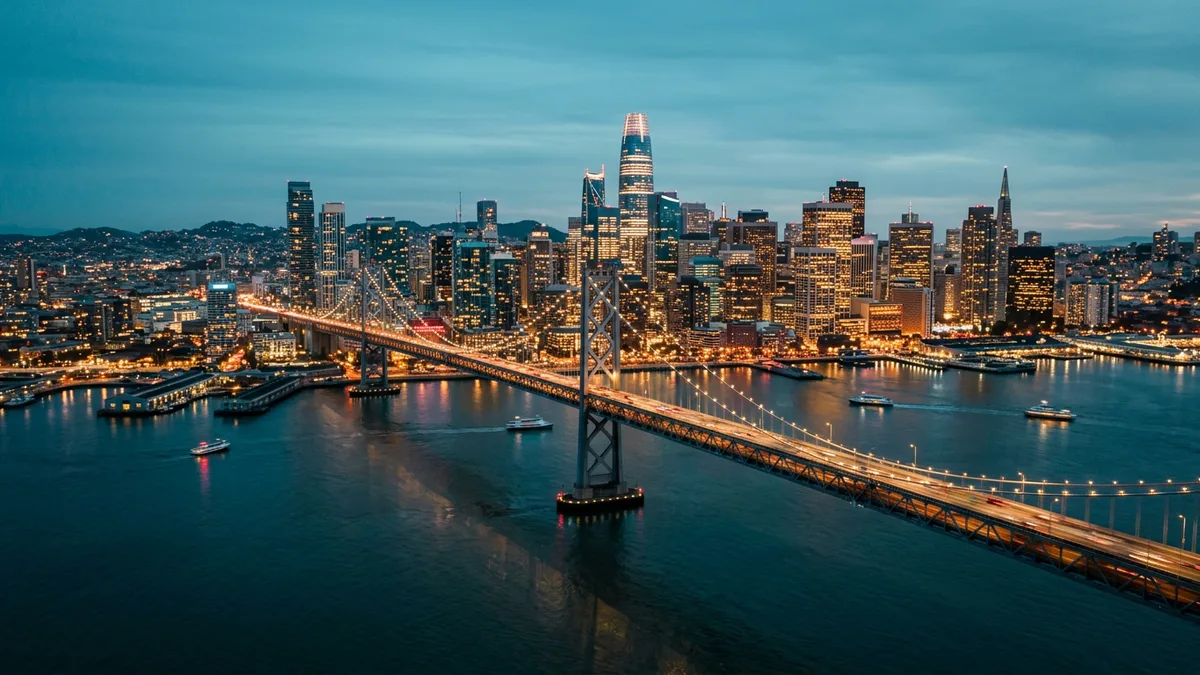 San Francisco skyline and Bay Bridge lit at blue-hour dusk, the metro KORE1 serves for cybersecurity staffing