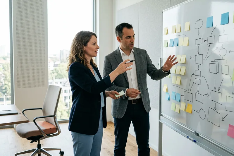 Engineering manager and KORE1 advisor mapping sprint capacity on a whiteboard covered in planning notes