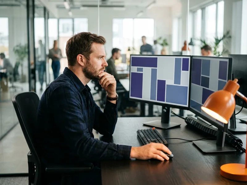 Software engineer watching a merge queue back up on a two-monitor workstation, 2026 engineering velocity benchmarks