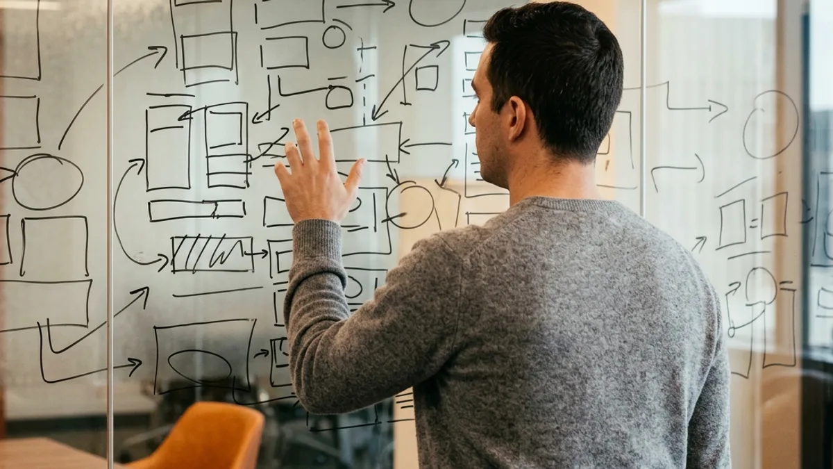 Engineering leader sketching an abstract decision-rights map on a glass wall to diagnose an inherited engineering organization