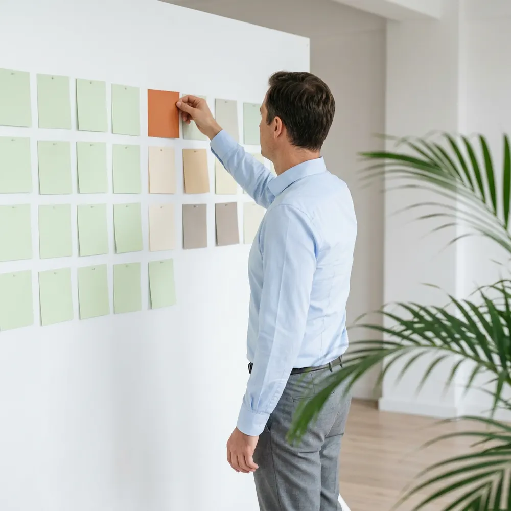 A hiring manager moving a card on a wall planning board during an SAP program scheduling session