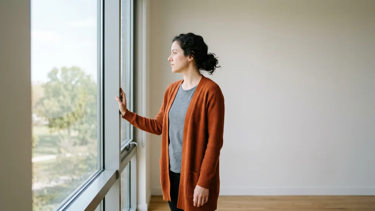 Marketing professional standing at an office window, representing a strong candidate who scrolled past a job title that signalled the wrong level