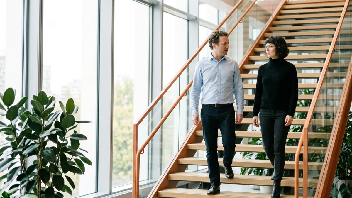 Hiring manager and senior engineer talking through MLOps on-call and reporting lines on an office staircase
