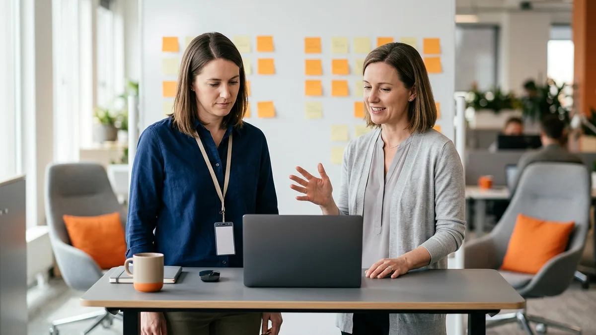 Contractor wearing a visitor lanyard and a full-time team lead reviewing a backlog together at a standing desk